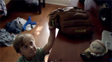 Young boy reaching for a glove to play with his older brother who mentors him.